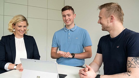 Drei HOWOGE Mitarbeiter stehen an einem Tisch