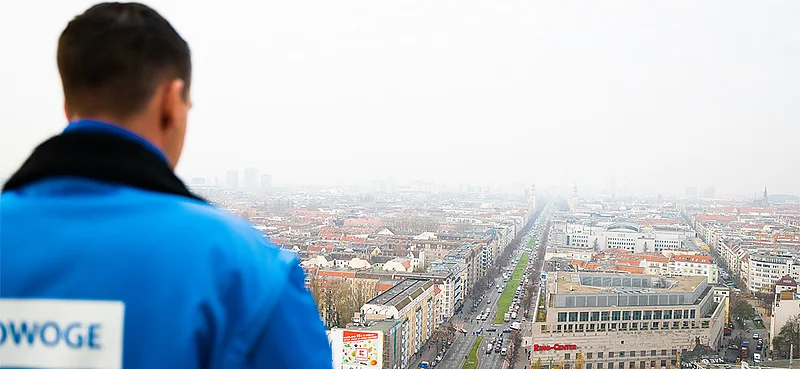 Mann in HOWOGE-Jacke blickt von oben über die Stadt Berlin