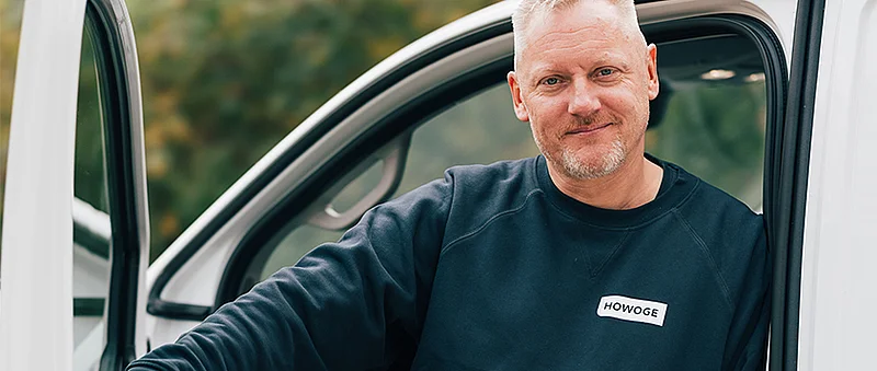 Sven Wagner steht in dunklem Sweatshirt an der Tür eines weißen Firmenfahrzeugs.
