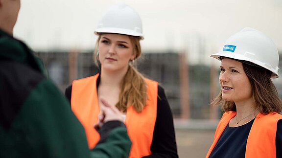 Zwei HOWOGE MItarbeiterinnen mit Bauhelm und Weste