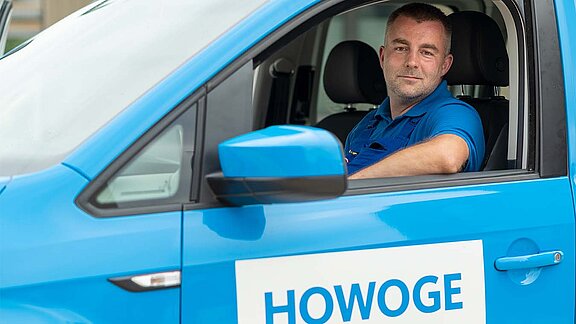 Hausmeister schaut aus Fenster eines HOWOGE Autos