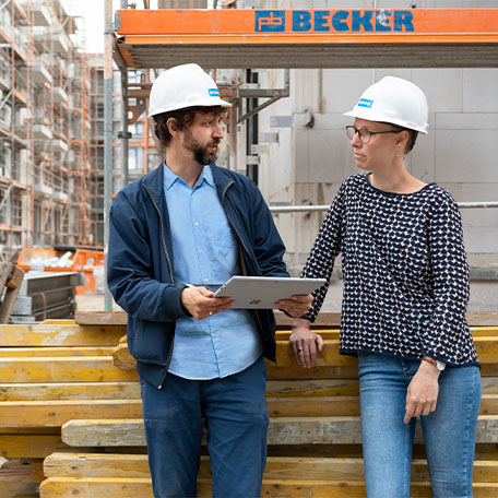 2 Kollegen mit Bauhelm unterhalten sich auf der Baustelle